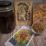 Display with St Johns Wort tincture in jar, three different tarot- and oracle cards that uses St. Johns Wort and lastly a small glass jar with dried St johns Wort.