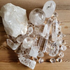 Photo shows a bundle of clear quarts crystals. Spheres, raw, freeform, tumbled stones. Hues from white to clear.