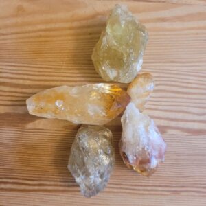 Collection of raw citrin and  tumbled stone. Raw citrin is in burned version with amber hues and as completely natural with a yellowish green hue.